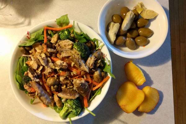 Une salade avec des olives et des pêches sur une table.