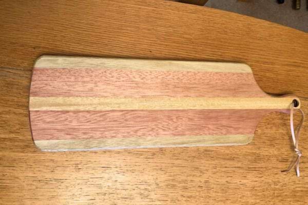 une planche à découper en bois avec un trou dans le manche pour la suspendre