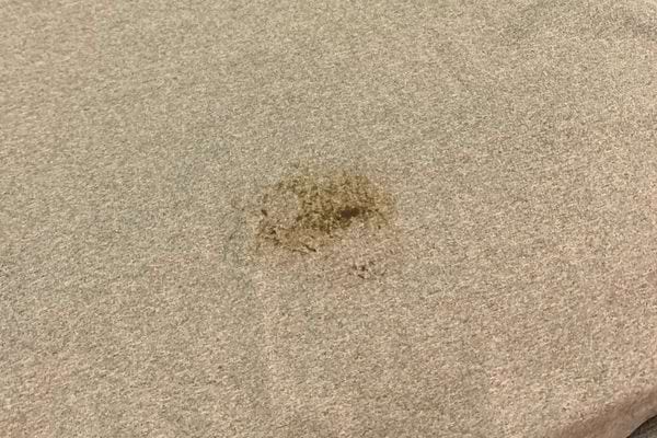 Tache de goudron sur tissu beige.