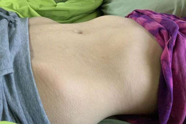 Un ventre plat vu de dessus, allongé sur un lit.