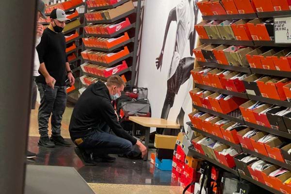 Homme essayant des chaussures dans un magasin, entouré de boîtes.