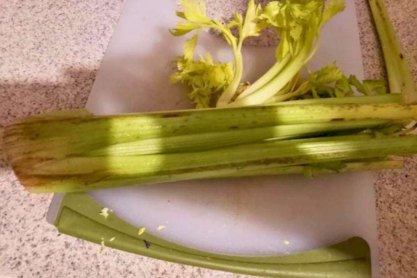 Branche de céleri partiellement coupée sur une planche.
