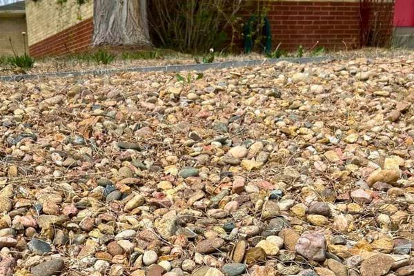 Graviers naturels étendus dans un jardin, nettoyeur haute pression jaune à côté.