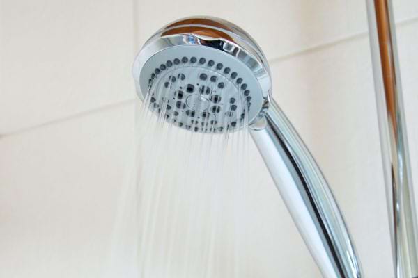 Douche argentée avec un mur blanc en arrière-plan.