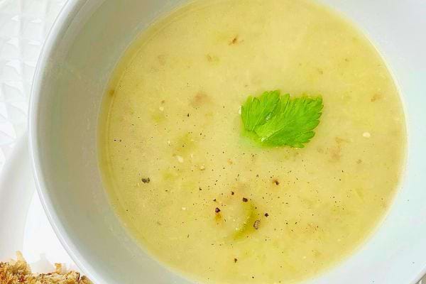 Soupe crémeuse avec une feuille de céleri et du poivre.