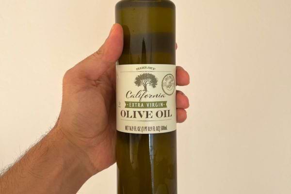 Bouteille d'huile d'olive extra vierge Californienne tenue par une main.