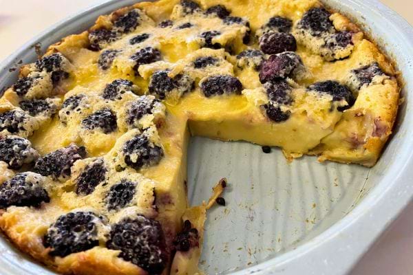 Clafoutis moelleux aux mûres avec une part coupée.