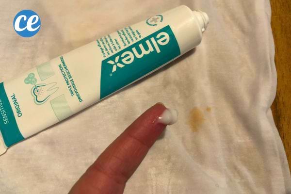 Dentifrice appliqué sur une tache de ketchup sur un tissu blanc.
