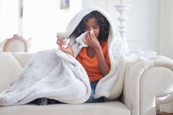 Une femme malade est enroulée dans une couverture.