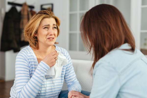 Une femme pleure, mouchoir en main.