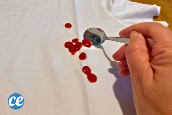 Cuillère avec du ketchup sur un t-shirt blanc.