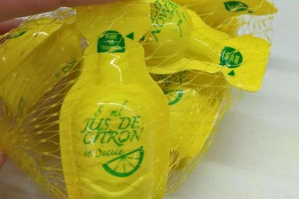 Petites bouteilles individuelles de jus de citron en plastique jaune.