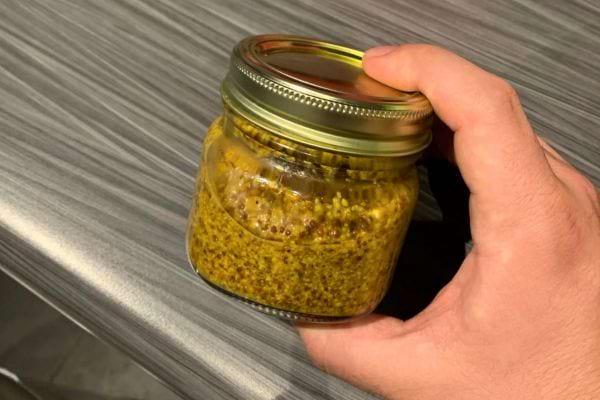 Petit bocal de moutarde avec grains entiers.