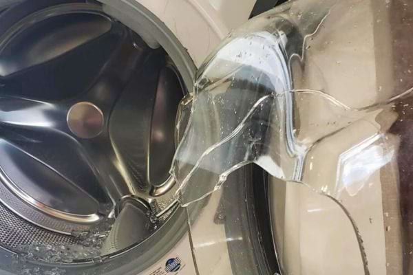 Porte de lave-linge avec verre brisé.