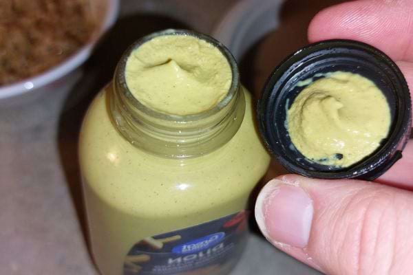 Pot de moutarde ouvert avec un bouchon rempli.