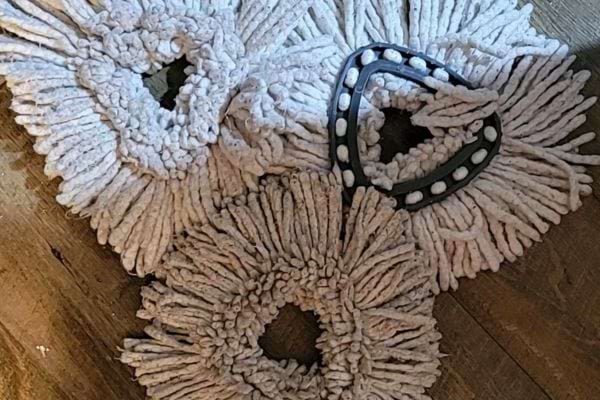 Trois serpillières blanches en tissu avec un support en plastique noir.