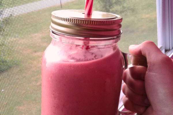 Smoothie rose dans un bocal avec paille.