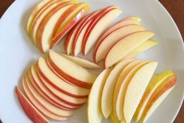 Des tranches de pommes sont disposées dans une assiette blanche.