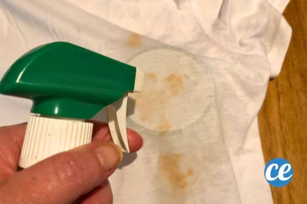 Spray de vinaigre appliqué sur une tache de ketchup sur un tissu blanc.