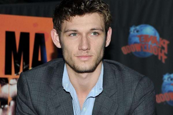Alex Pettyfer en costume, cheveux décoiffés.