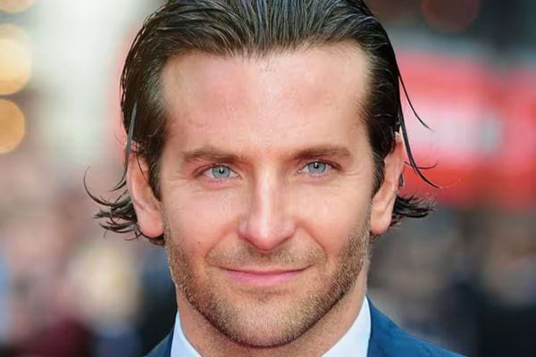 Bradley Cooper, cheveux plaqués en arrière, souriant.