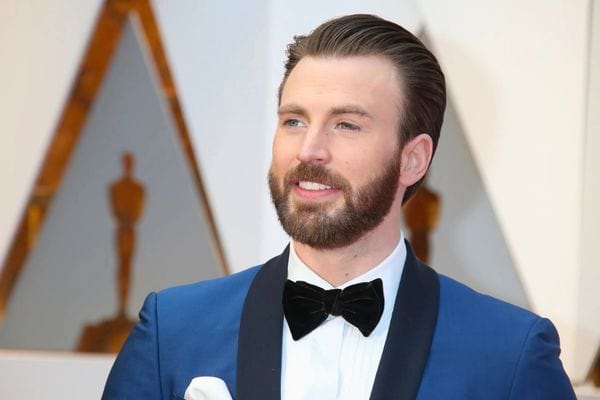 Acteur Chris Evans en costume bleu avec nœud papillon.