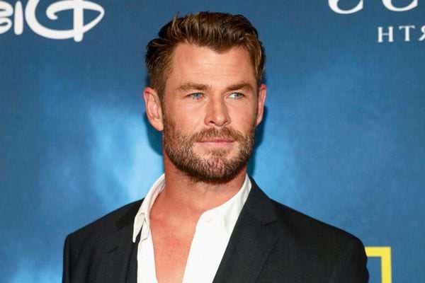 Chris Hemsworth en veste noire, chemise blanche décontractée.