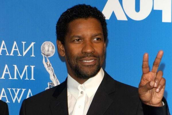 Denzel Washington faisant un signe de paix en costume.