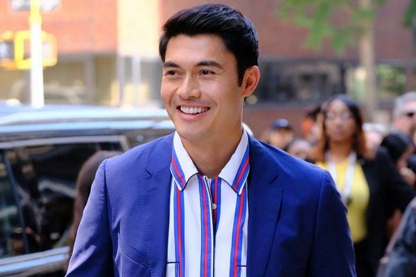 Henry Golding en costume bleu rayé.
