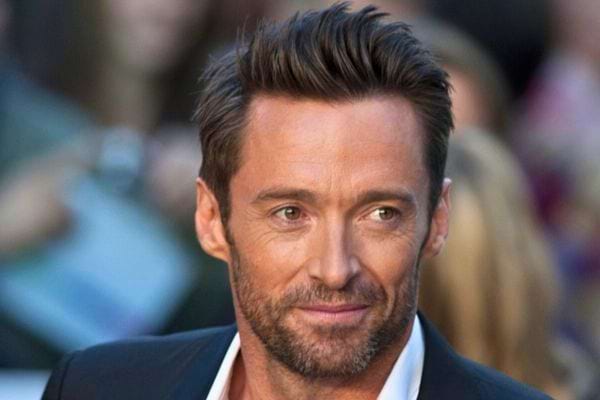 Hugh Jackman souriant en costume noir.