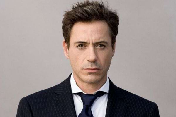 Robert Downey Jr en costume noir avec un regard sérieux.