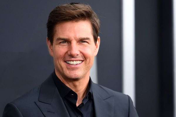 Tom Cruise souriant en veste noire.