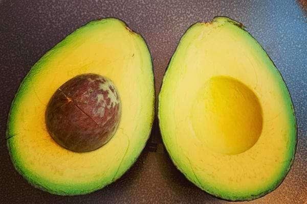 Avocat coupé en deux sur une surface.