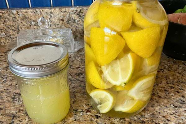 Bocal de citrons frais infusés dans de l’eau avec un bocal de jus à côté.