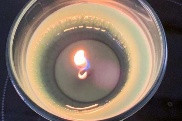 Bougie partiellement fondue avec une flamme au centre.