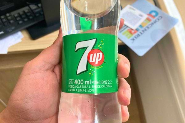 Bouteille de 7up tenue en main.