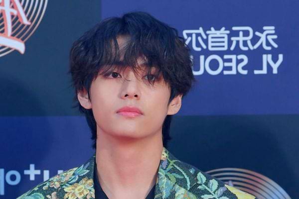 Kim Taehyung en tenue colorée, regard sérieux.