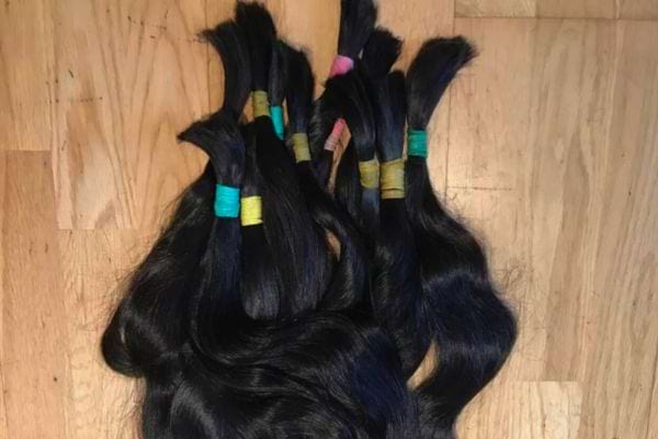 Cheveux noirs coupés en mèches, posés sur un sol en bois.