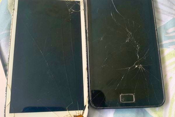 Deux téléphones portables avec écrans fissurés côte à côte.