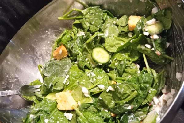 Épinards frais avec concombres et croutons dans un bol.