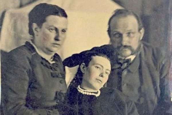 Photo de famille ancienne avec trois personnes posant solennellement.