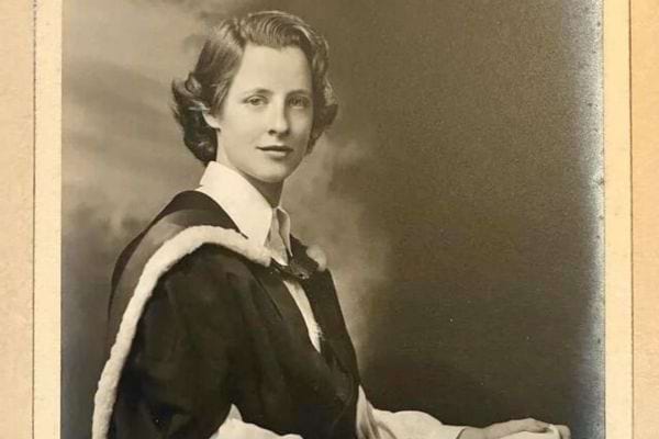 Femme en robe de diplômée posant pour un portrait en noir et blanc.