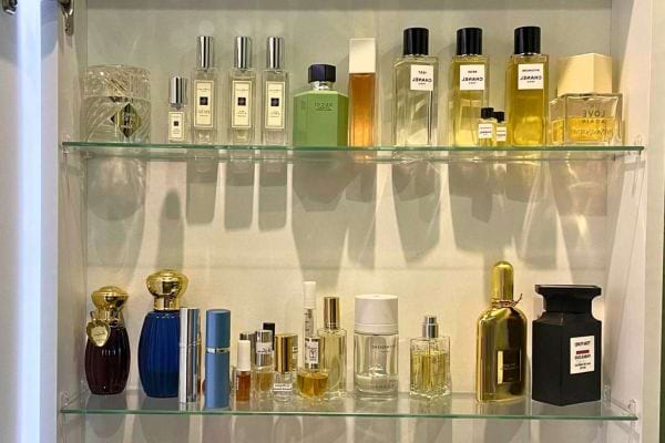 Flacons de parfums alignés sur des étagères en verre.