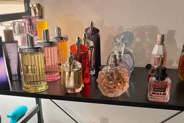 Flacons de parfums colorés en verre sur une étagère noire.