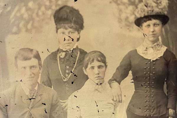 Photo ancienne de quatre personnes en habits du XIXe siècle, sérieux.