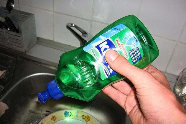 Bouteille de liquide vaisselle versant du produit dans l’évier.