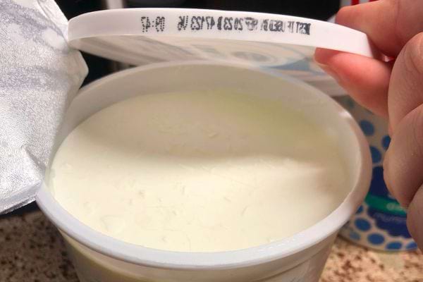 Ouverture d'un pot de yaourt blanc.