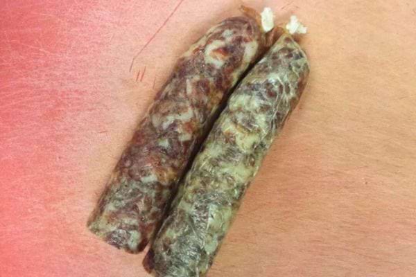 Deux petits saucissons secs pos&eacute;s sur une surface.