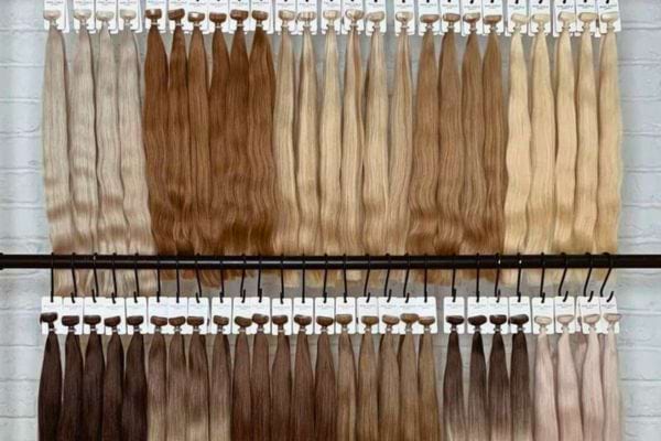 Rangées de mèches de cheveux de différentes couleurs sur un support.