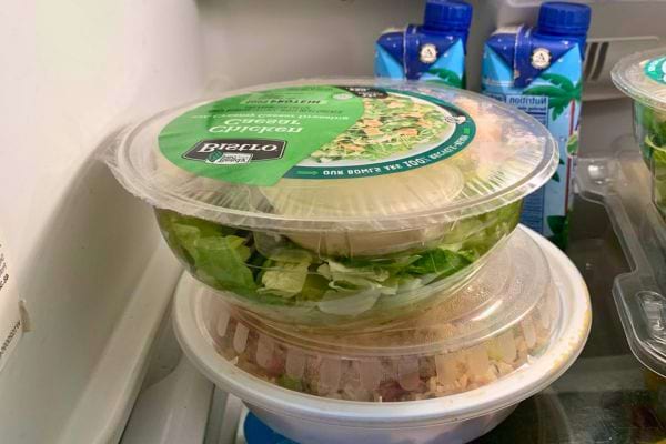 Salade de poulet prête à manger dans un emballage empilé au frigo.
